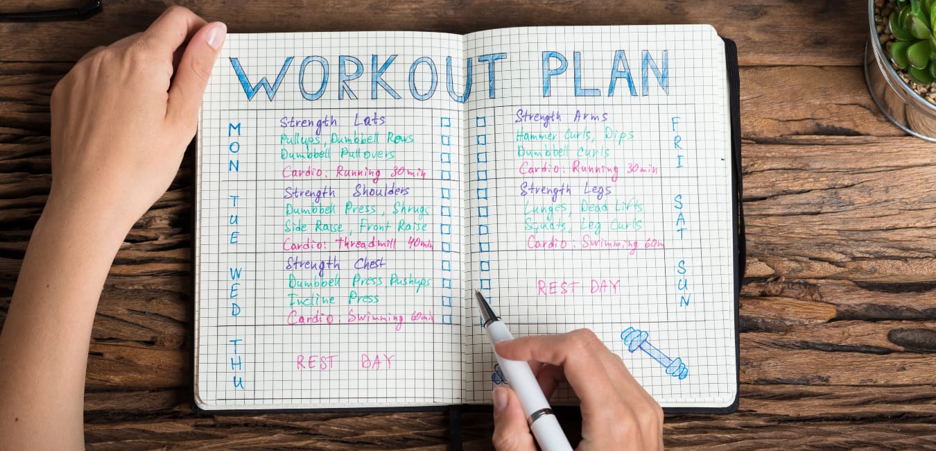 How to make a workout plan. Woman's hands drawing up a workout plan in a colorful journal.