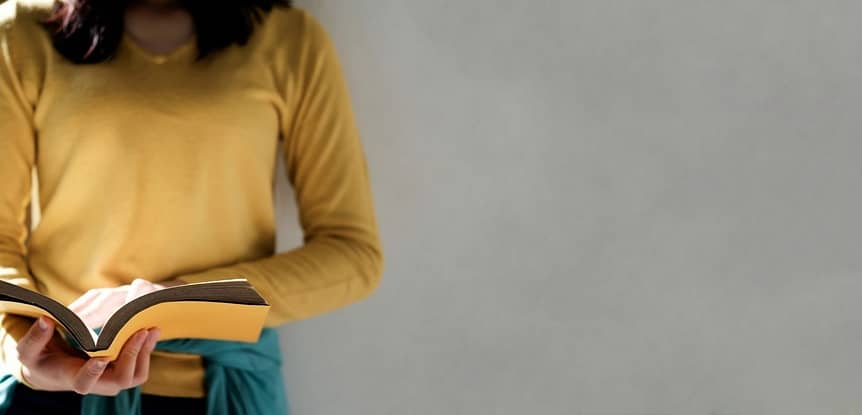 Challenge Yourself to Learn Something New. Woman in yellow long sleeved shirt reading a yellow book.