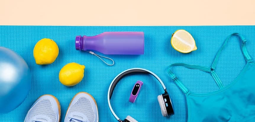 The TED of Fitness Workout Motivation. Aqua exercise mat with gym shoes, purple water bottle, lemons, headphones, teal sports bra, purple fitness tracker.