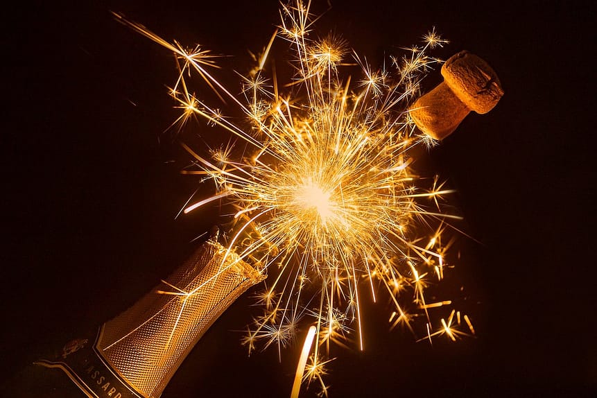 fitness resolutions for the new year. Dark background, gold champagne bottle bursting open with sparkler.