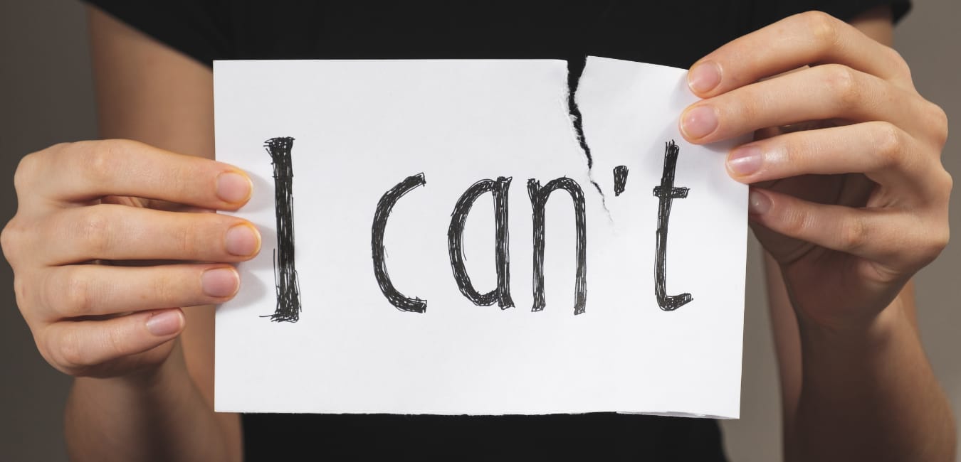 Realizing you can do what you want to achieve. Woman's hands holding a sign that says "I can't" and tearing off the 't'.