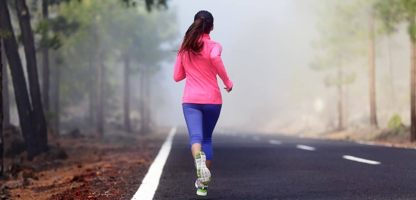 Fitness Routines Work, But Only If You Make Them Your Own. Woman in hot pink jacket running on a foggy road.